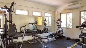 Ein Fitnessstudio mit Trainingsgeräten, großen Fenstern und einer Klimaanlage.