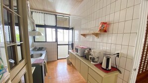 Una cocina compacta con pileta, estufa y un ventanal con cortinas.