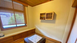 Una habitación japonesa tradicional con suelo de tatami, una mesa de madera baja y una ventana con paneles shoji.