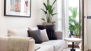 Ett modernt vardagsrum med en beige soffa, ett runt soffbord och en stor krukväxt.