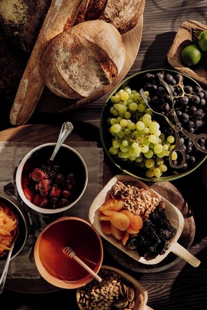 A variety of food items including bread, grapes, and nuts arranged on a wooden table.