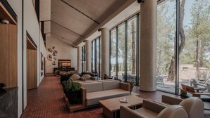 A spacious lounge area with a long bench, sofas, and a coffee table. Large windows provide a view of the outdoors. - KeyUrla (Urla)