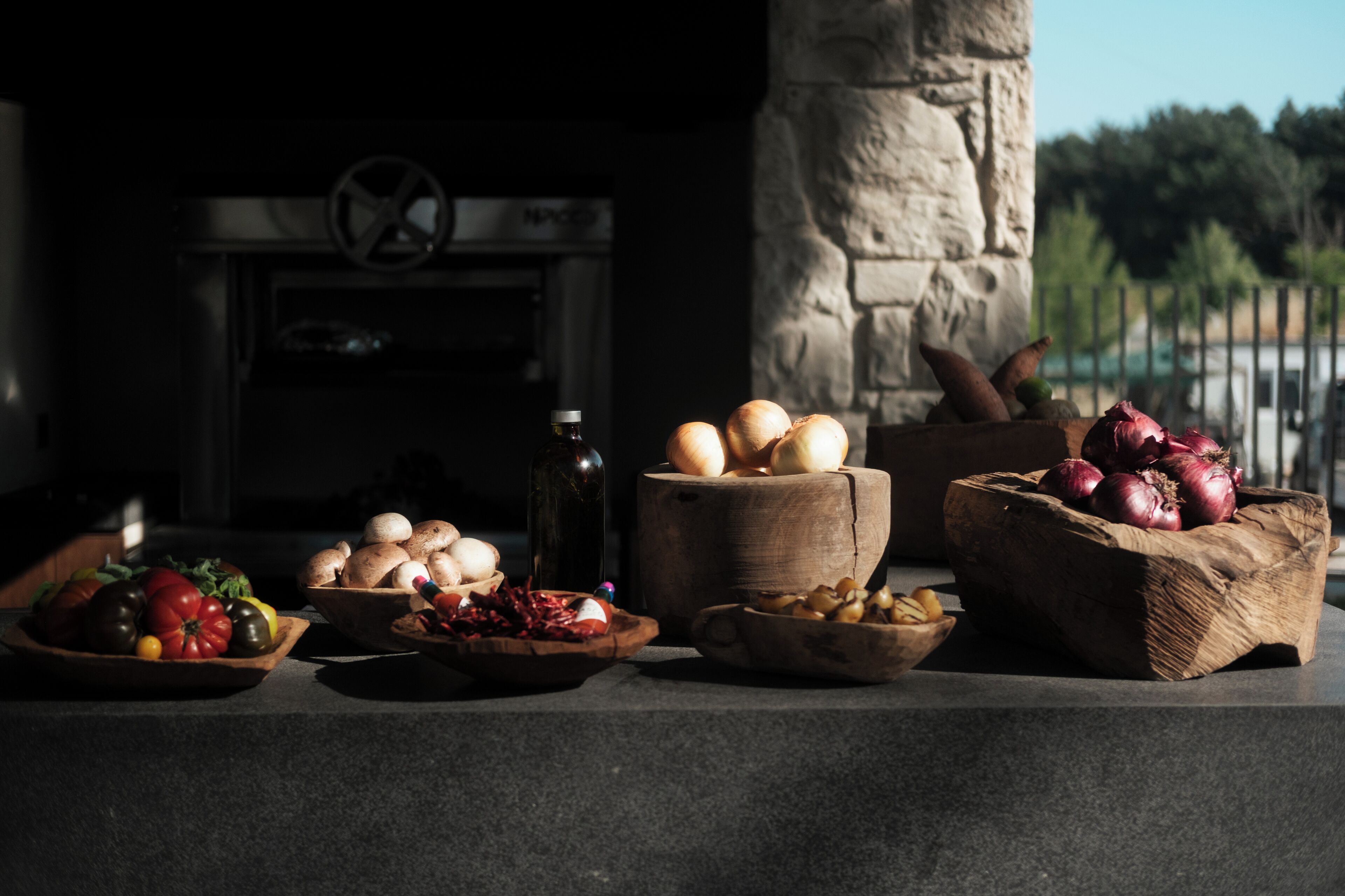 Una chimenea de piedra con diversas frutas y verduras dispuestas sobre una encimera.