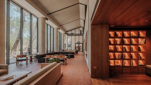 A modern interior with a long bench seating area, a wooden bookshelf, and large windows providing natural light. - KeyUrla (Urla)