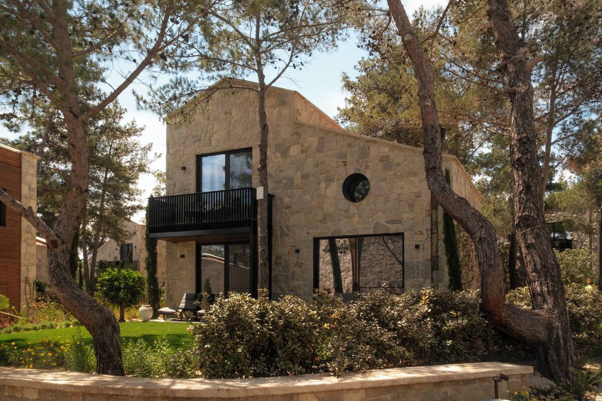 A stone building with a balcony, surrounded by trees and greenery.