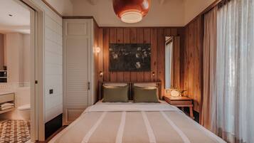 A bedroom with a large bed, wooden panel walls, a bedside table with a lamp, and a painting on the wall.