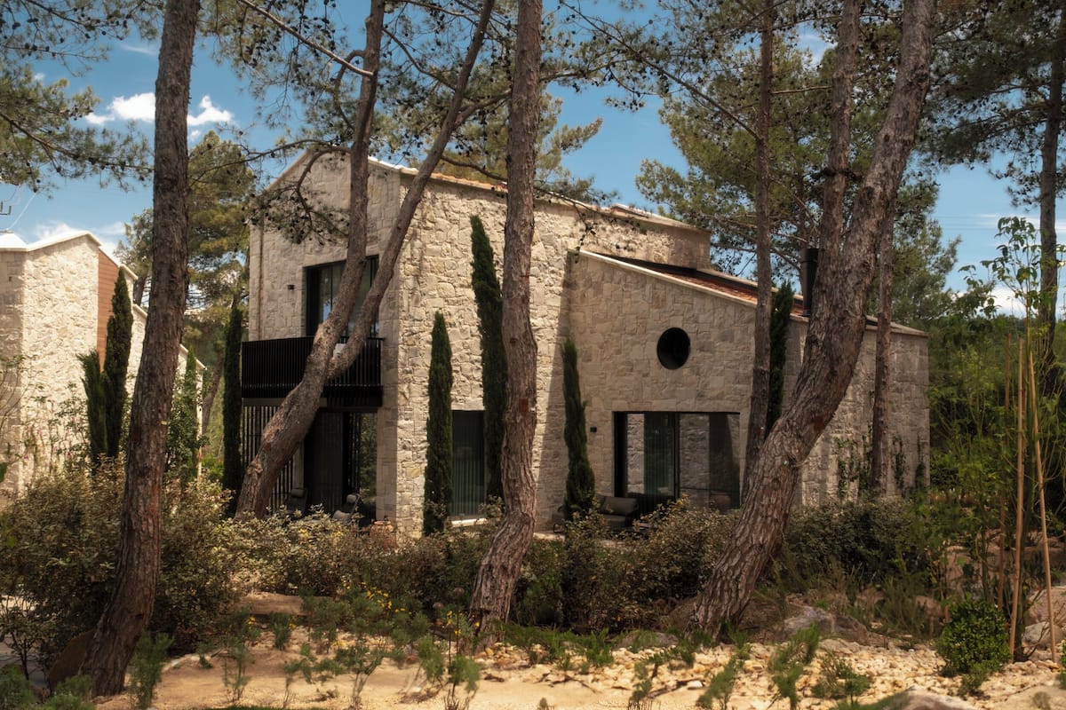 A stone building with a modern design, surrounded by trees and vegetation.
