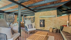 Un intérieur chaleureux avec un mur en briques, une cheminée, des meubles en bois et un plafond avec des poutres apparentes.