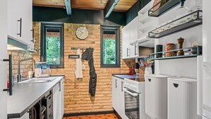 Une cuisine avec un mur en briques, une horloge et une enseigne indiquant « CUISINE ».