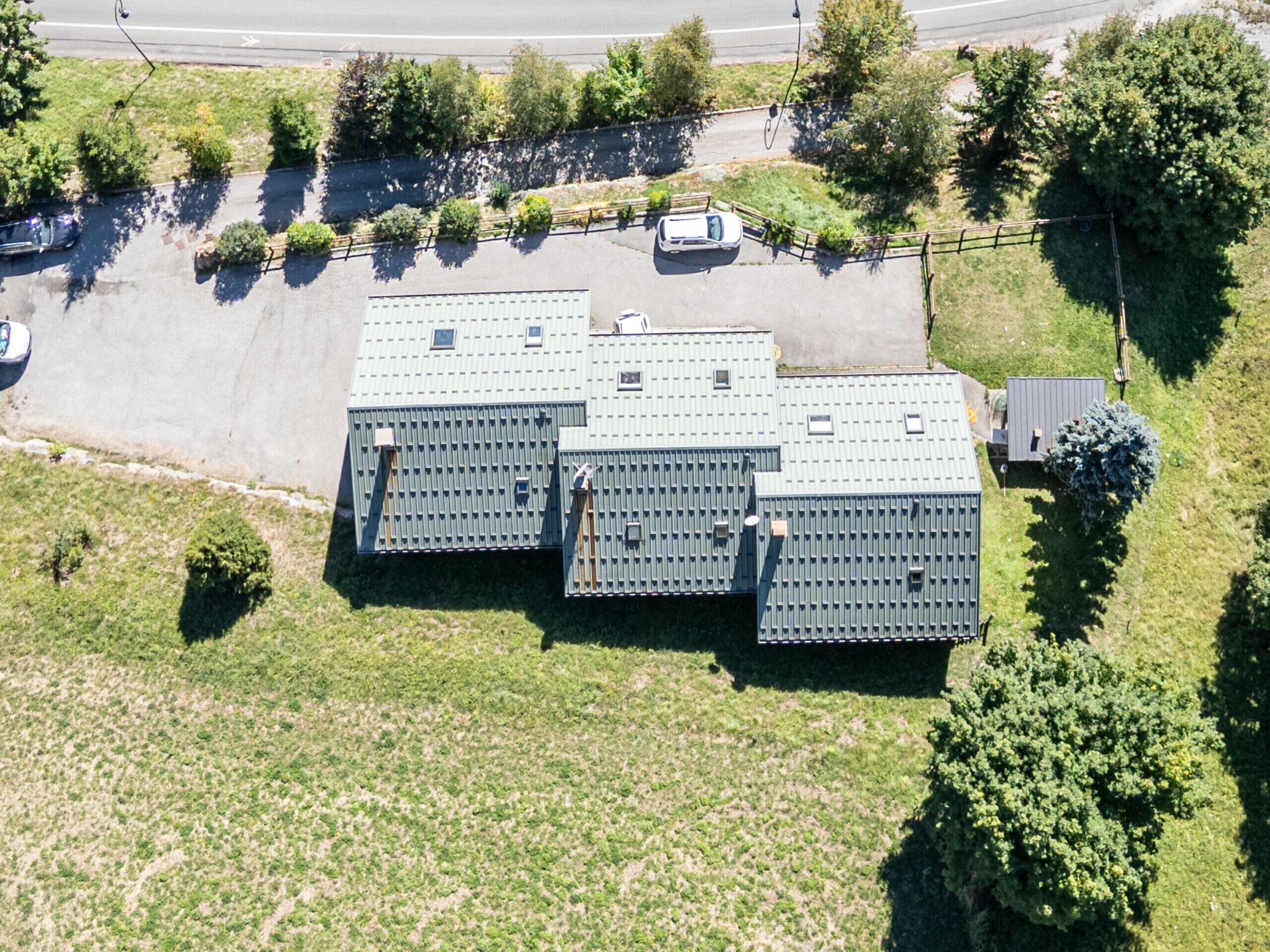 An aerial view of a parking lot with three large, rectangular buildings with flat roofs.