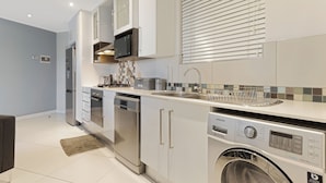 Una cocina moderna con electrodomésticos de acero inoxidable, lavavajillas integrado y lavadora.
