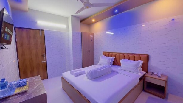 Een moderne hotelkamer met een bed, nachtkastje en plafondventilator.