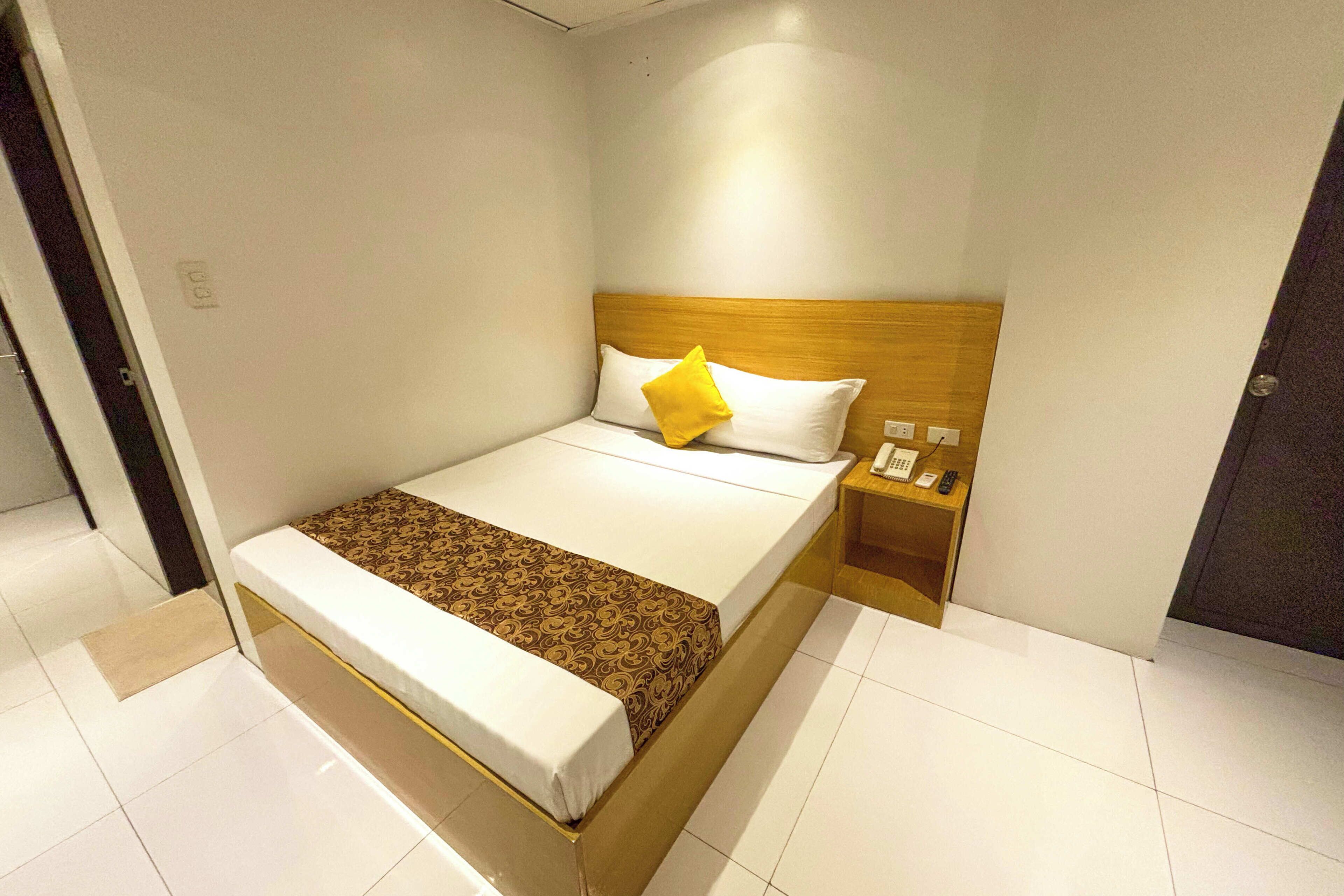 A hotel room with a bed, a bedside table, and a nightstand.