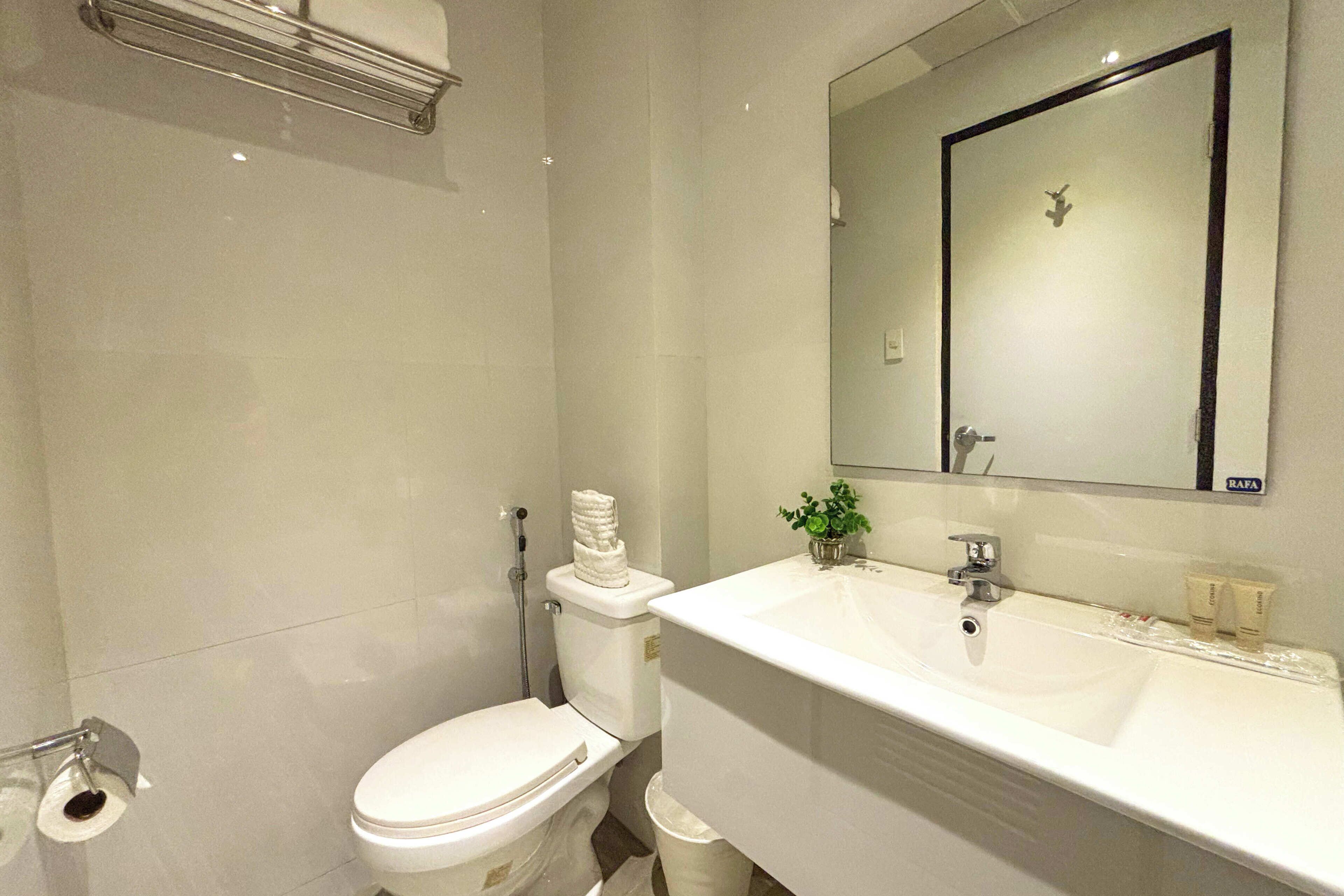 Un baño moderno con un inodoro blanco, un lavabo y un espejo.