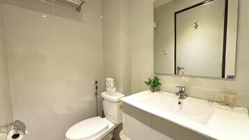 Un baño moderno con un inodoro blanco, un lavabo y un espejo.