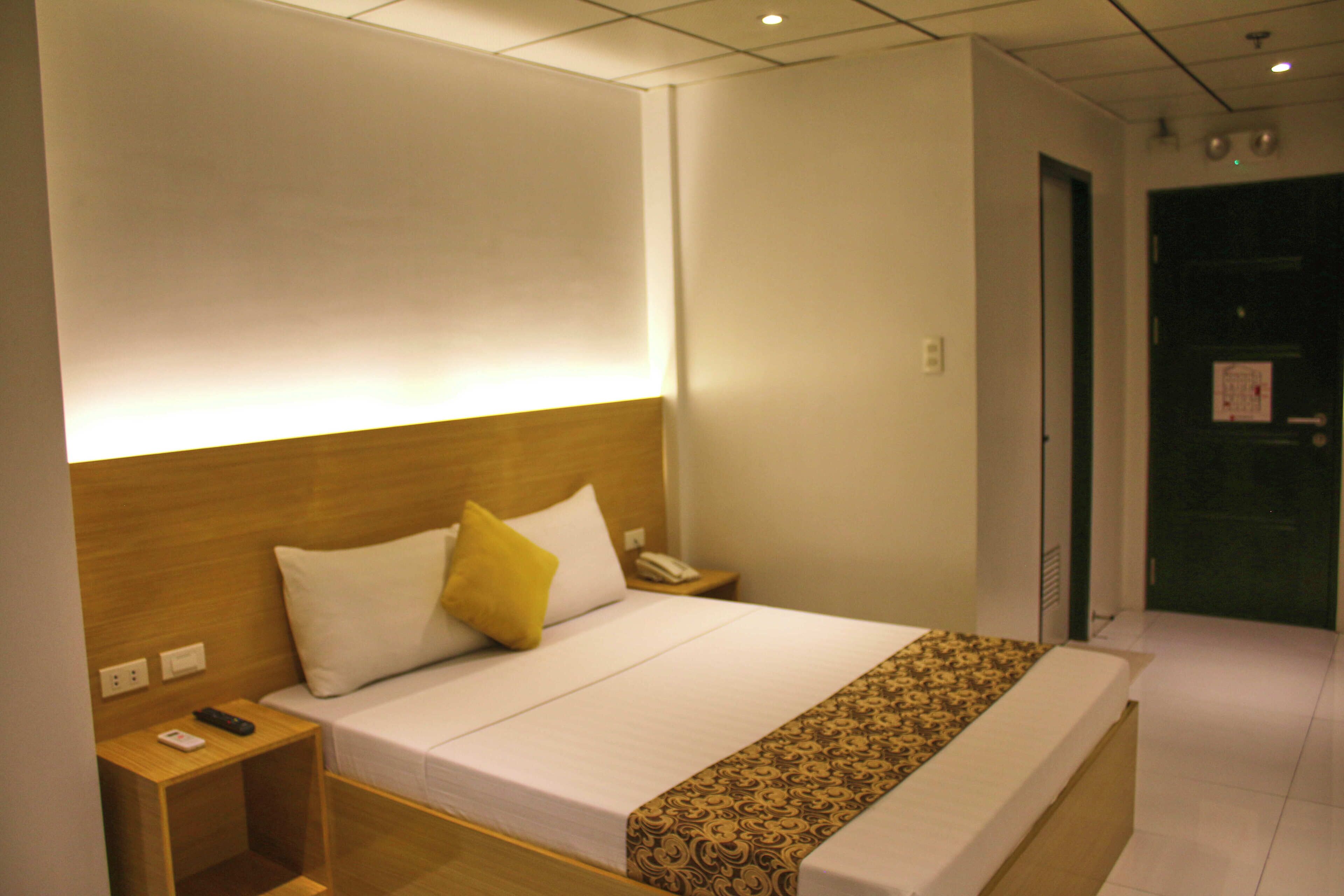 A hotel room with a bed, bedside table, and a nightstand.