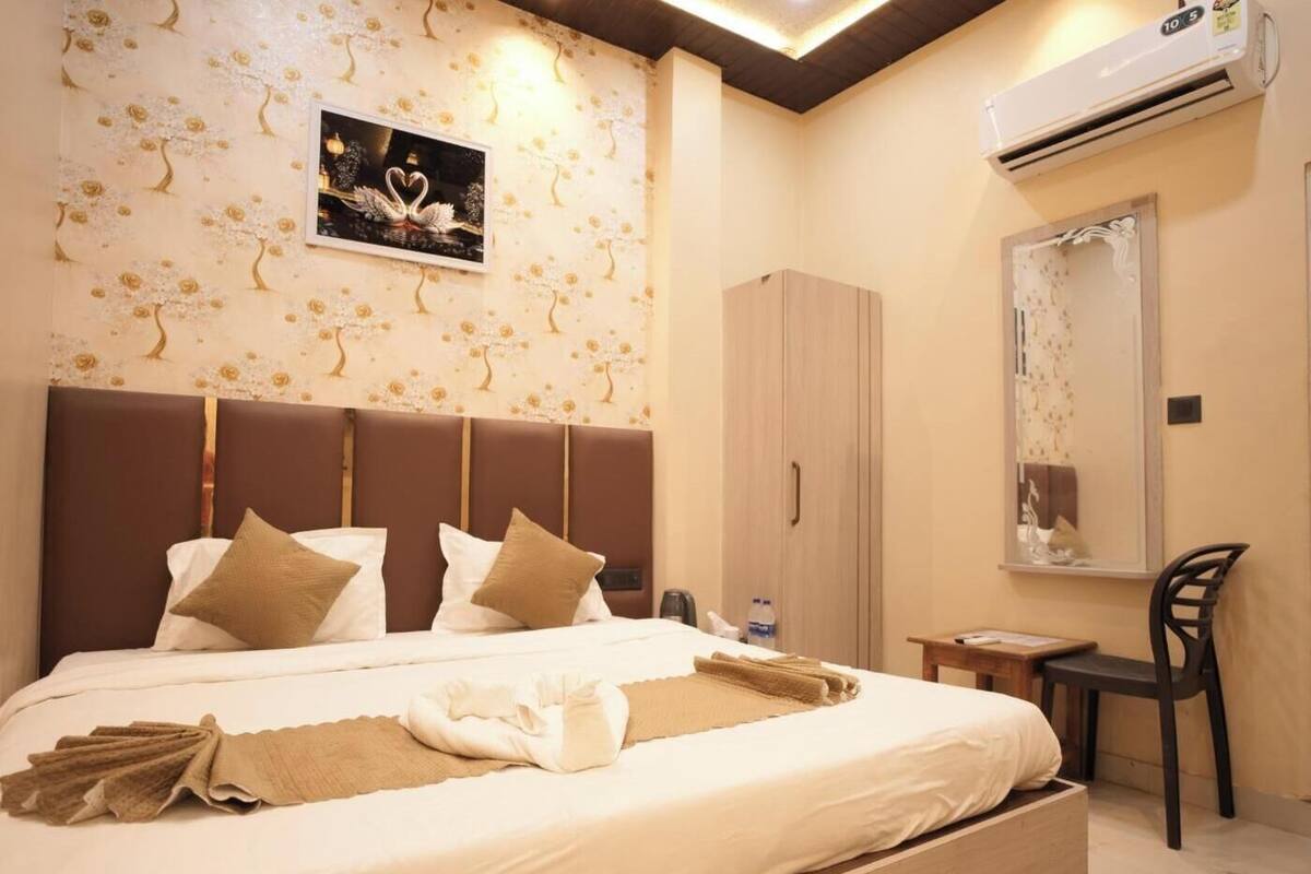A hotel room with a bed, a wardrobe, a desk, and a chair.