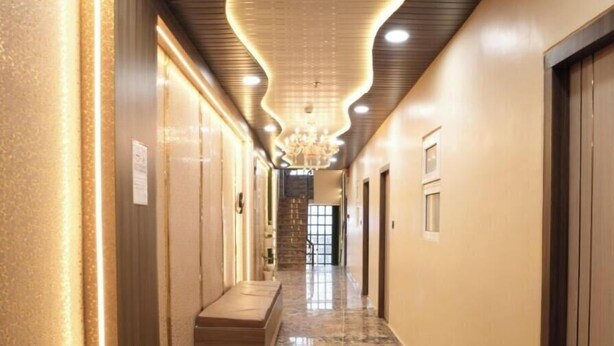 A hallway with a marble floor, recessed lighting, and a central staircase. - Shree Shiven Homestay (Varanasi)