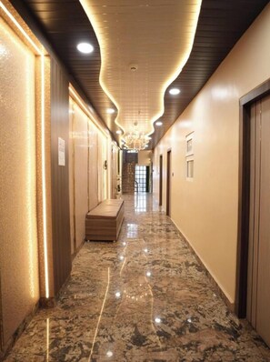 A hallway with a marble floor, recessed lighting, and a central staircase. - Shree Shiven Homestay (Varanasi)