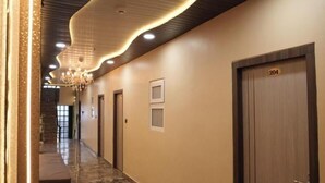 A hotel hallway with a marble floor, wooden doors, and a modern ceiling design. - Shree Shiven Homestay (Varanasi)