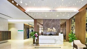 Zona de recepción de hotel con mostrador de mármol, un escritorio y un área de descanso con una silla.