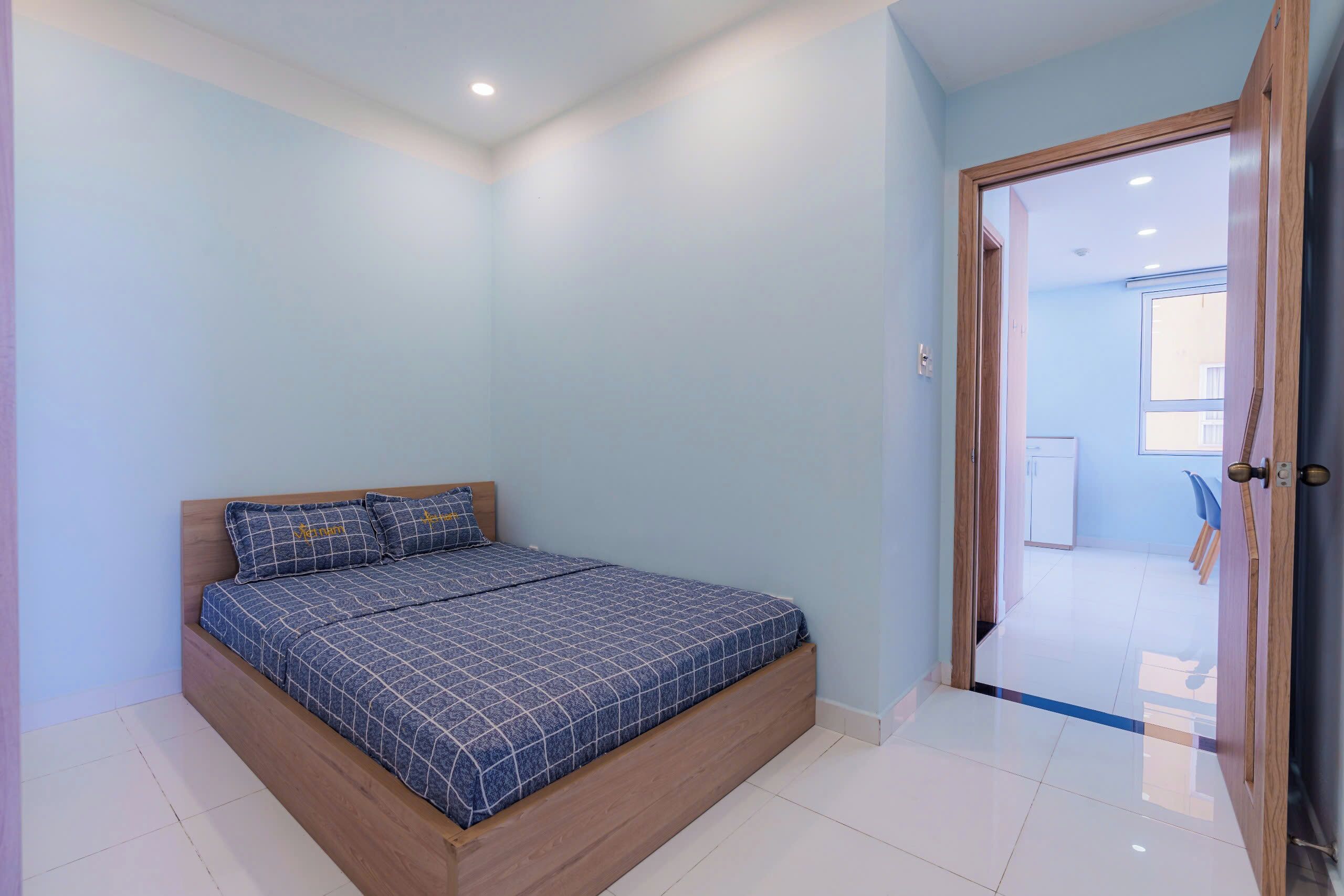 Een slaapkamer met een bed, een deur en uitzicht op een andere kamer.