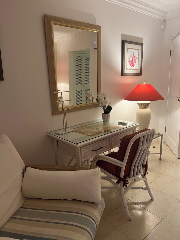 A bedroom with a bed, a desk with a mirror, a chair, and a lamp.