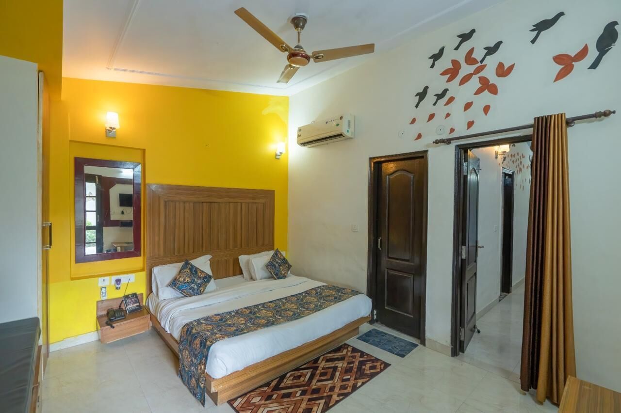 A bedroom with a bed, a ceiling fan, a wall-mounted air conditioner, and a door with a curtain.