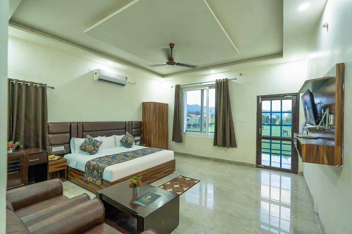 A hotel room with a bed, a desk, a chair, a TV, and a balcony with a view.