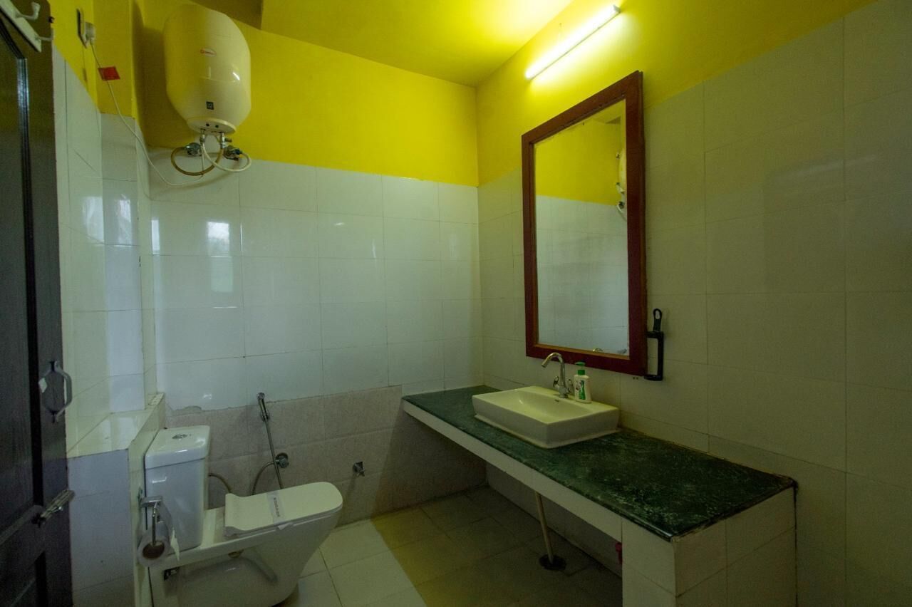 A bathroom with a white toilet, a sink with a mirror above it, and a shower area.
