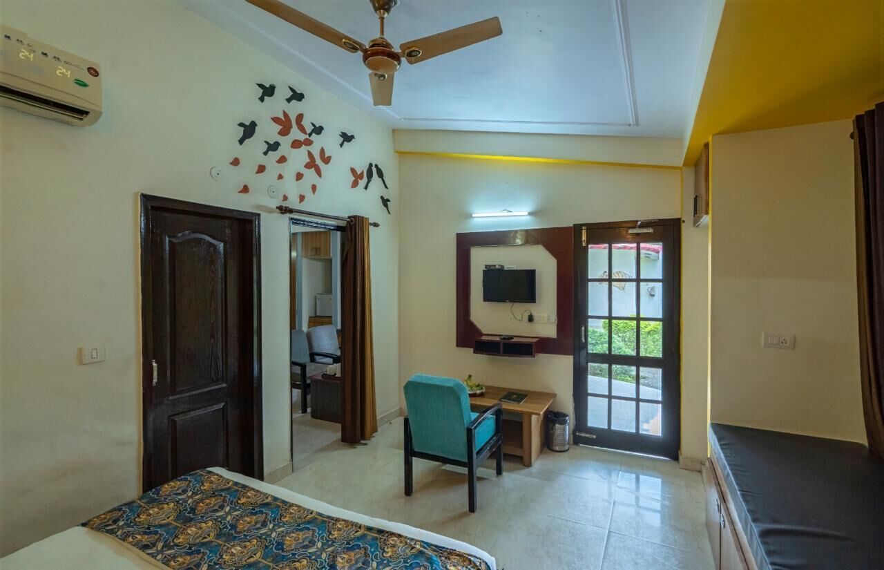 A hotel room with a bed, a desk, a chair, a television, and a window with curtains.