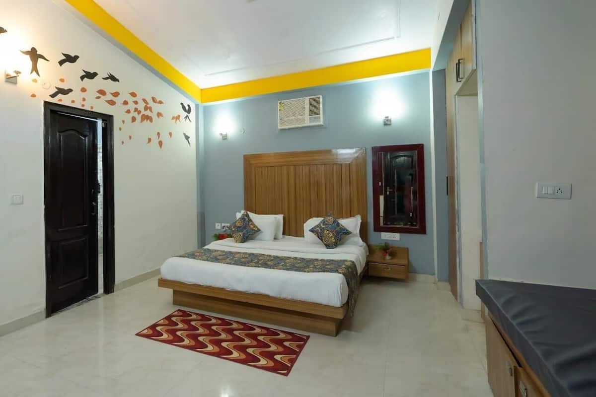 A bedroom with a bed, a wooden headboard, a nightstand, a bedside table, a mirror, and a red patterned rug.