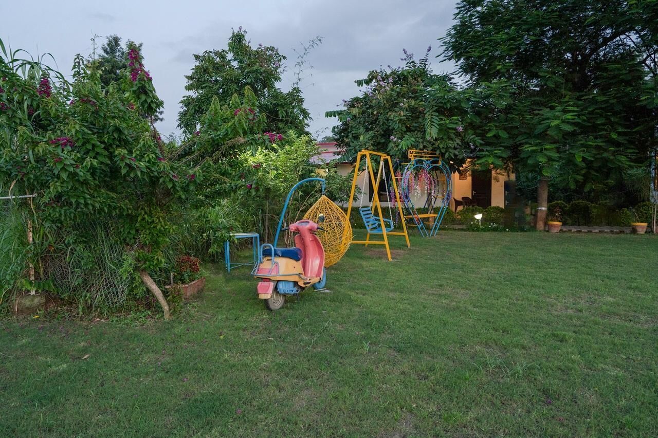 A garden with a swing set and a scooter.