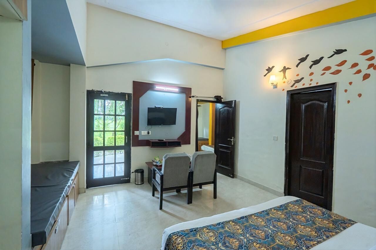 Un dormitorio con cama, escritorio, silla, televisor y puerta.