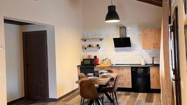Une cuisine moderne avec des meubles en bois, un coin repas doté d’un canapé jaune et un plancher en bois.
