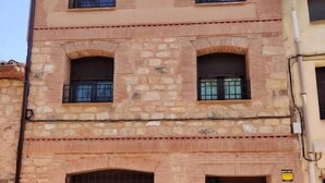 Un immeuble à plusieurs étages, doté d’une façade en pierre, de nombreuses fenêtres et d’une porte.