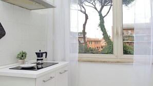 A modern kitchen with a stove, a coffee maker, and a small plant on the counter.