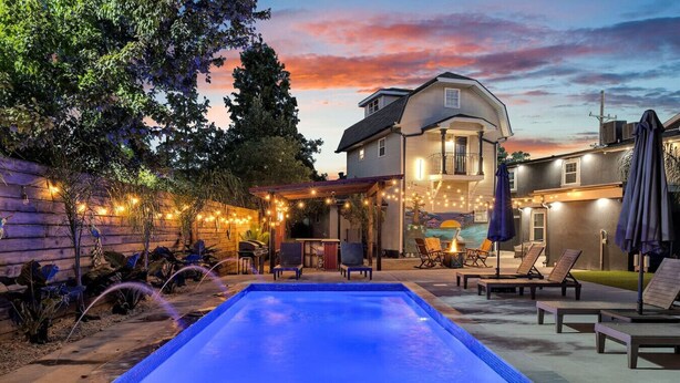 Une piscine avec un espace patio, des guirlandes lumineuses et du mobilier d’extérieur.