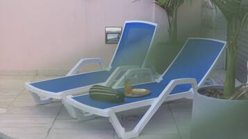 Two blue lounge chairs with white frames, a small table with a drink, and a potted plant.