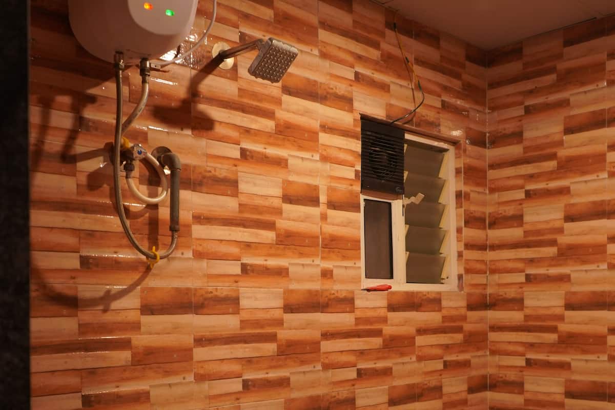 A bathroom with a wooden wall pattern, a toilet, a bidet, and a showerhead.