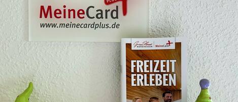 A promotional card for MeineCard PLUS and a brochure titled 'FREIZIT ERLEBEN' with a gnome figurine.