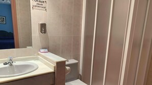 Un baño con lavamanos, inodoro y zona de ducha.