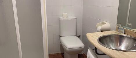 Une salle de bain avec des toilettes, un lavabo et un miroir.