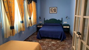 Un dormitorio con cama, mesita de noche, cómoda y ventana con cortinas.