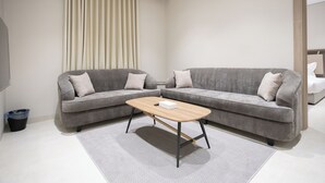 A modern living room with two grey sofas, a wooden coffee table, and a large window with curtains. - Manazel Marez 2 - private apartments (Madinah)