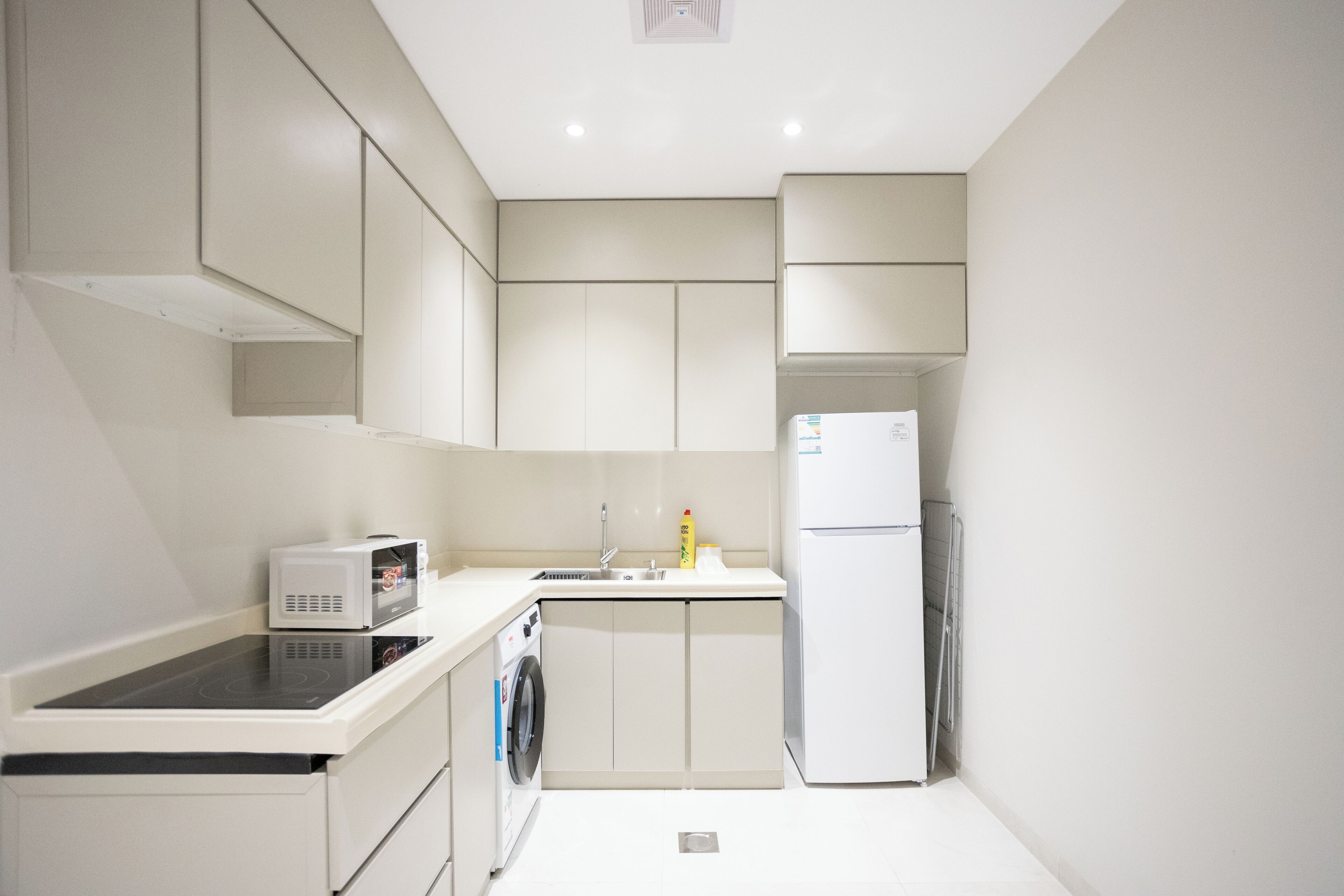 Eine kleine Küche mit Mikrowelle, Waschmaschine, Spüle und Kühlschrank.