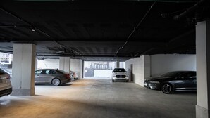 A parking garage with concrete pillars, a grey car, and a white car parked. - Manazel Marez 2 - private apartments (Madinah)