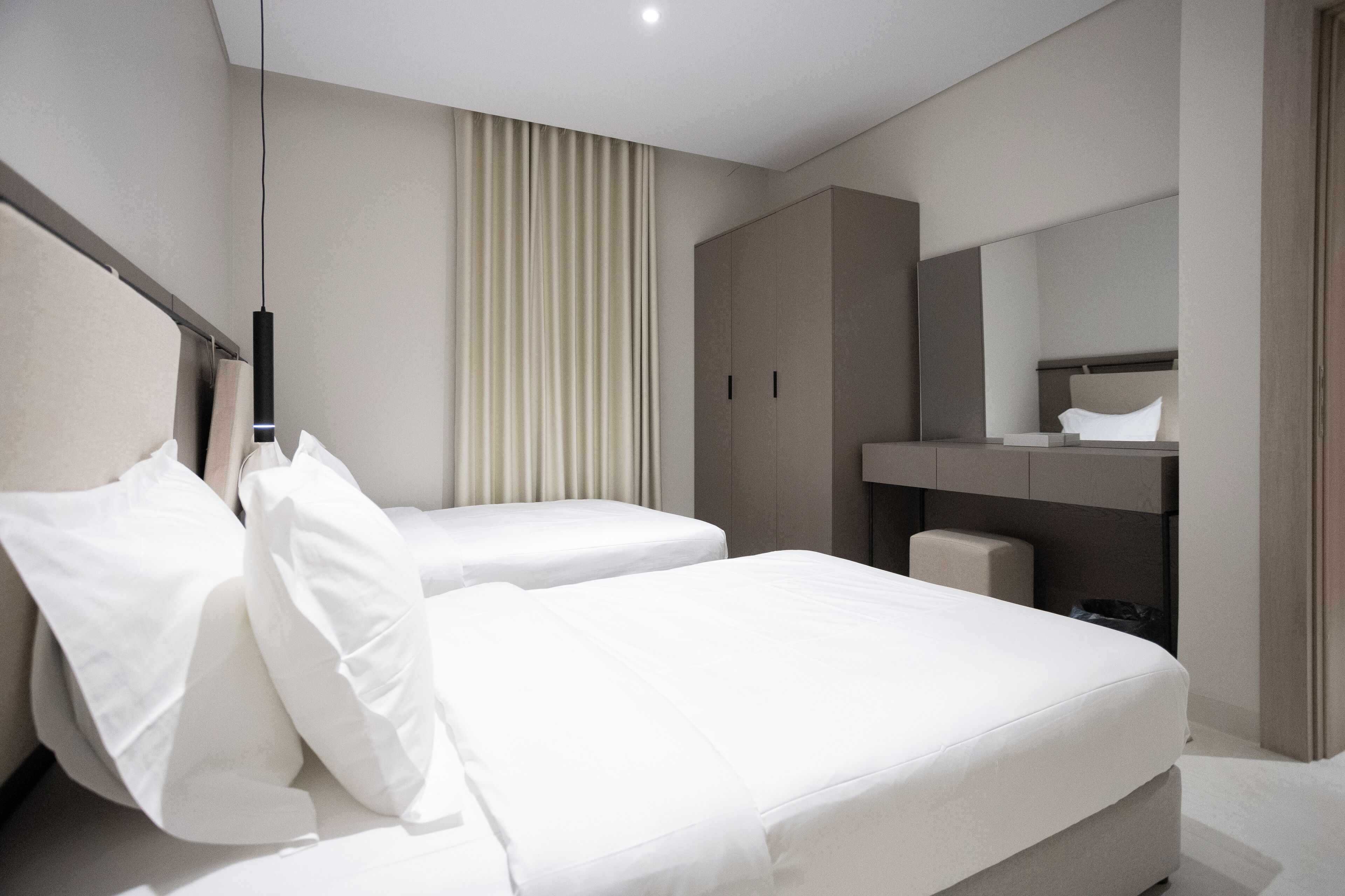 Une chambre d’hôtel moderne avec deux lits, un grand miroir et une armoire.