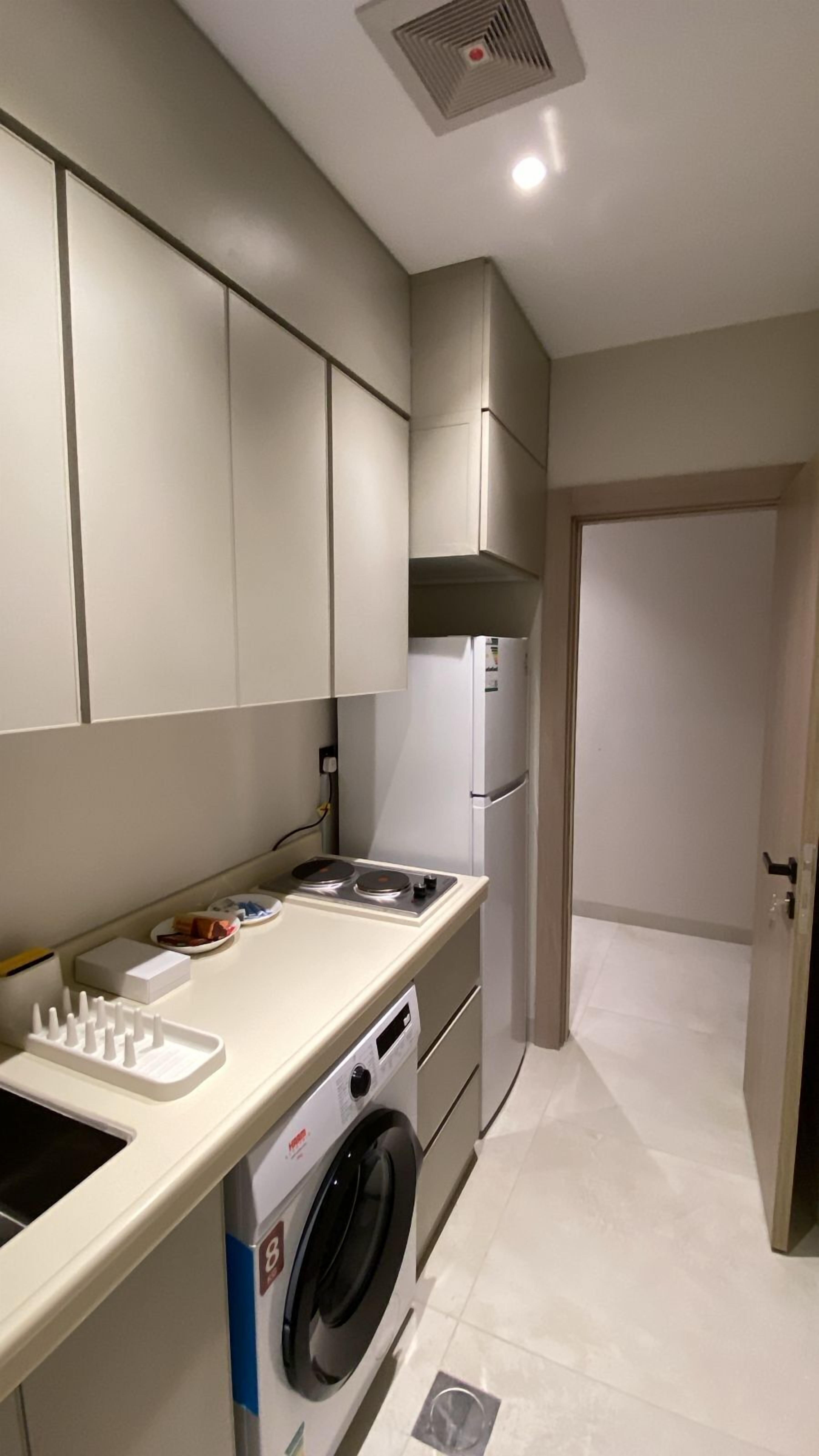 A compact kitchen with a built-in washing machine, a stove, and a refrigerator.