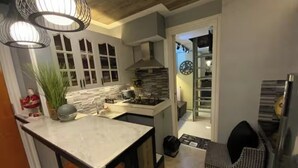 Una cocina moderna con encimera de mármol, estufa y lámpara colgante.